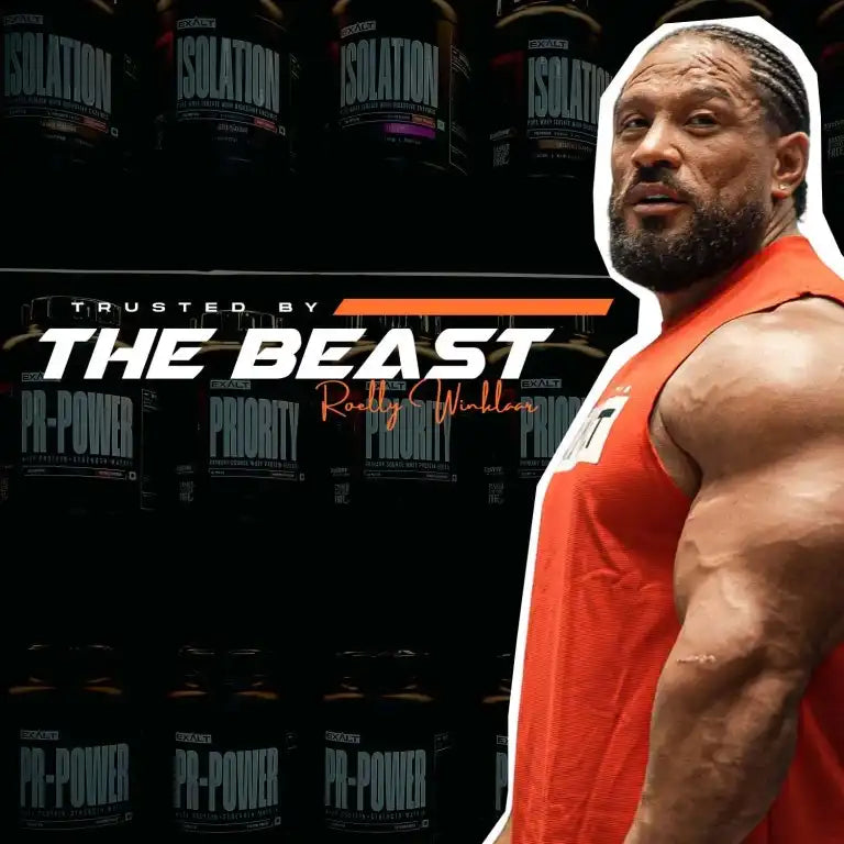 Muscular man in a red tank top with protein powder containers in the background